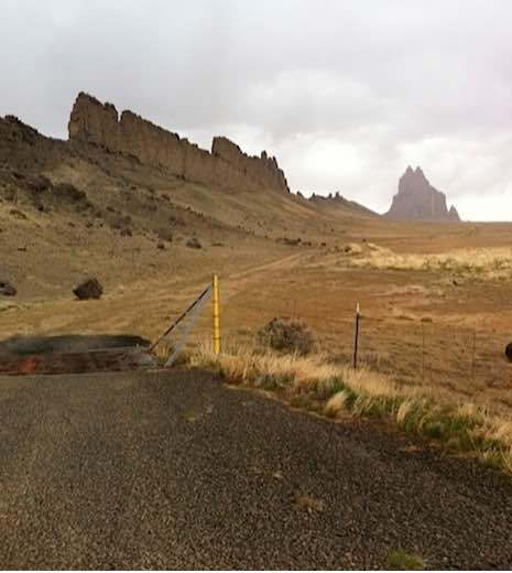 Photo: Shiprock landscape with road and telephone poles in foreground and rock formation in background