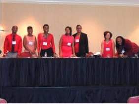Photo: Student participants in conference pose behind conferencetable