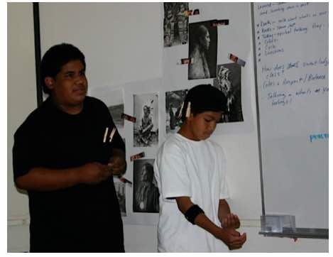 Photo: Young boy at white board in classroom with NAISC scholar.