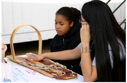 Elvina Charley uses the cradle board to discuss concepts and meaning with young student.   