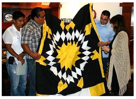 Photo: Graduates present Dr Robinson-Zañartu with a star quilt 