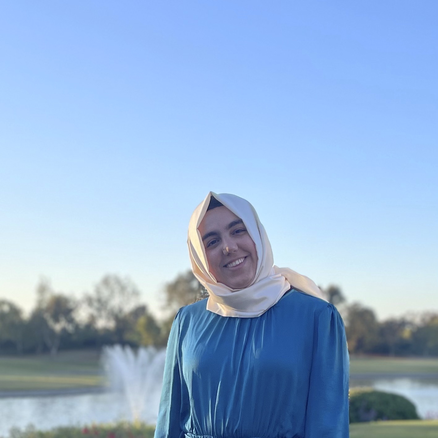 nihan wearing blue shirt with white hijab and fountain background