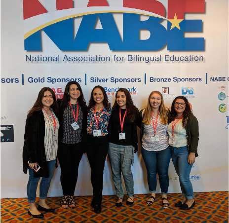 Photo: PUEDE! scholars pose in front of signage at NABE conference, 2019.