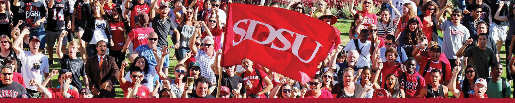 faculty, staff and students march with SDSU flag