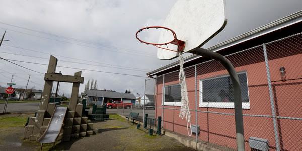 Basketball hoop and a red building is to the side of the hoop. 